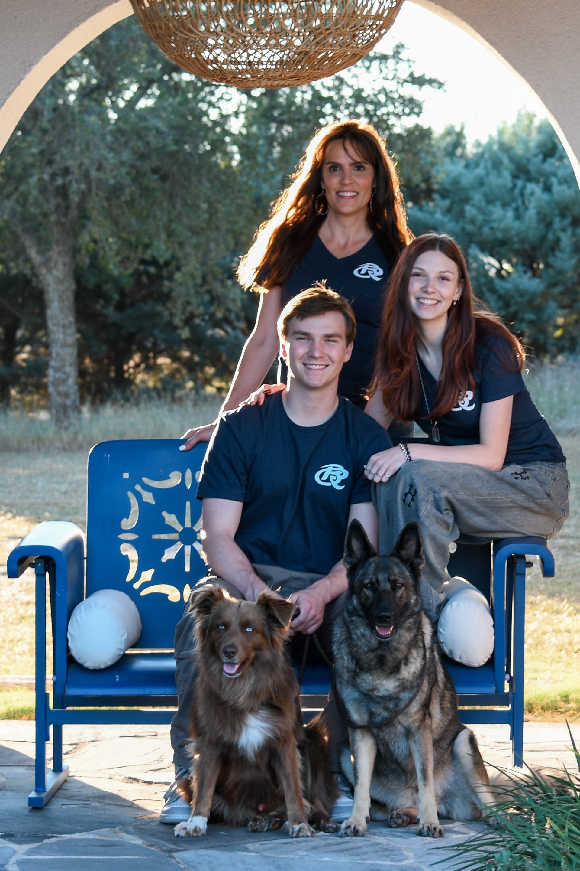 Kyle Family of with two dogs sitting on a blue bench outdoors.
